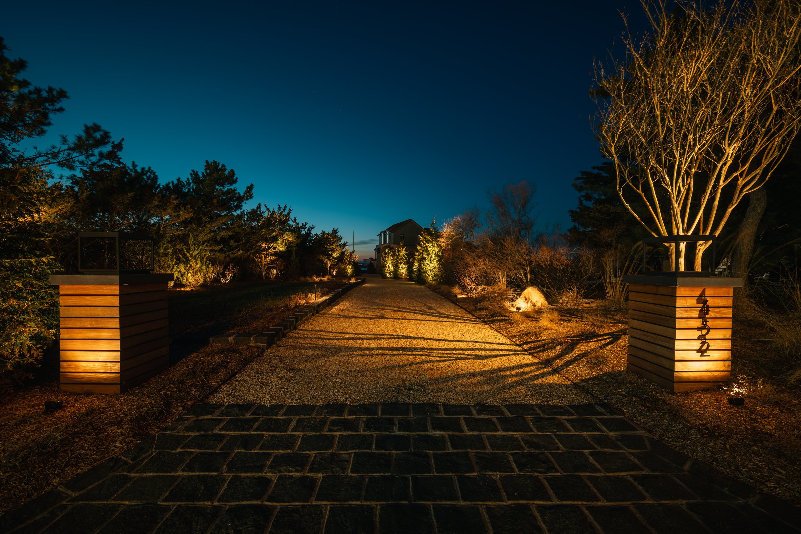 Long Island outdoor lighting along a driveway with illuminated stone pillars